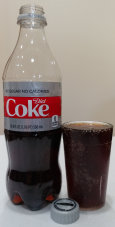 A partially filled bottle of Diet Coke next to a full glass. The glass is too small to hold all of the Coke.