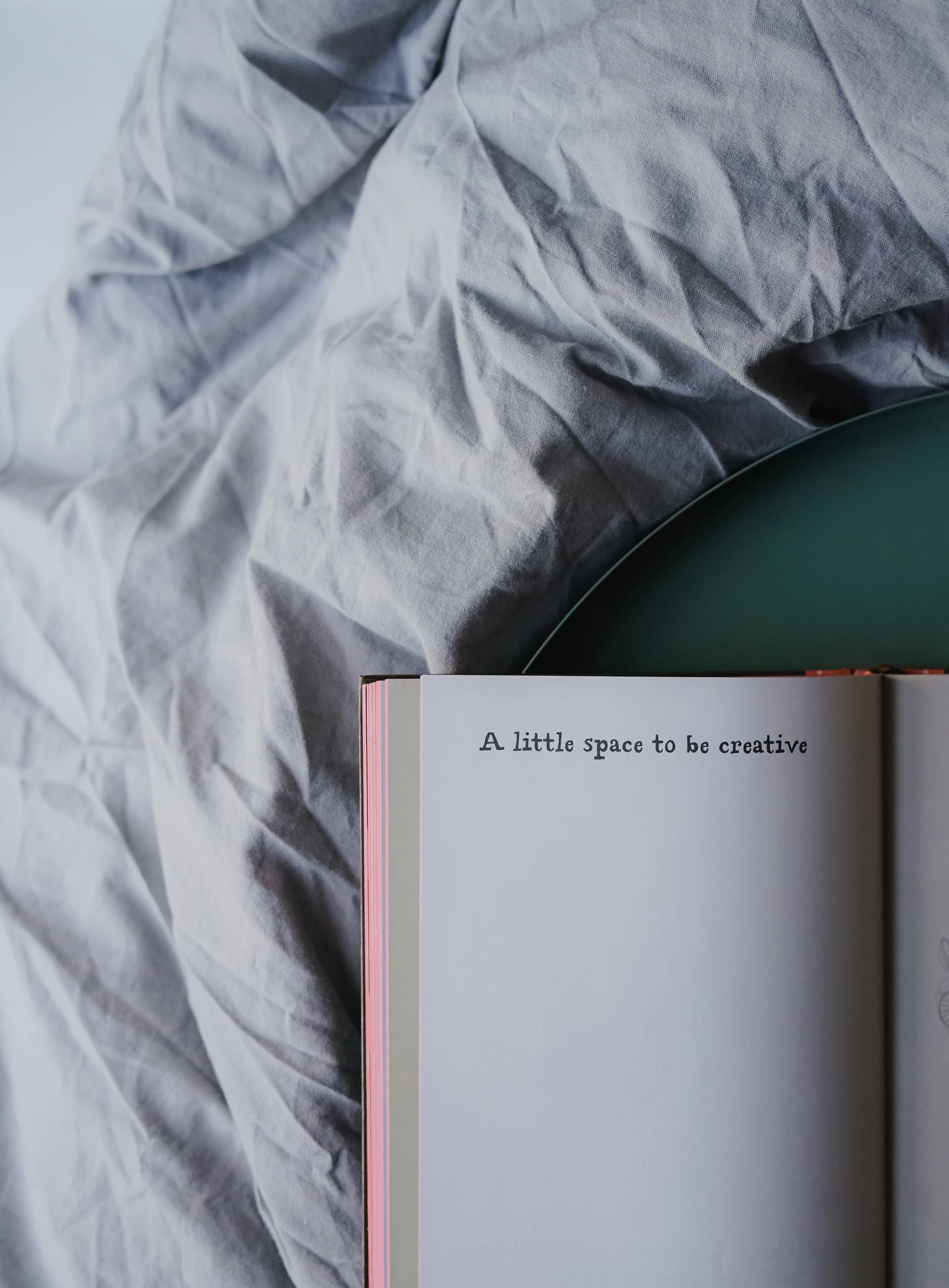 book with text 'a little space to be creative' on bed sheet
